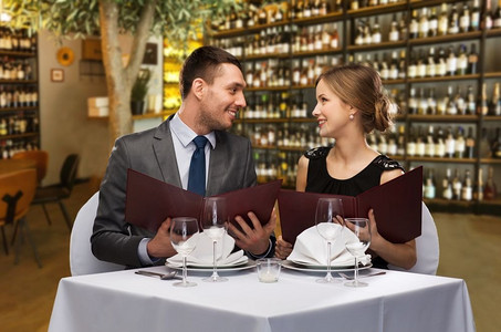 休闲和豪华概念—有菜单的微笑夫妇在餐馆或葡萄酒酒吧背景。在餐厅或酒吧菜单的快乐夫妇
