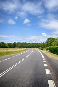 弯曲泼墨摄影照片_弯曲的道路在一个农村农村风景在蓝天下在夏天