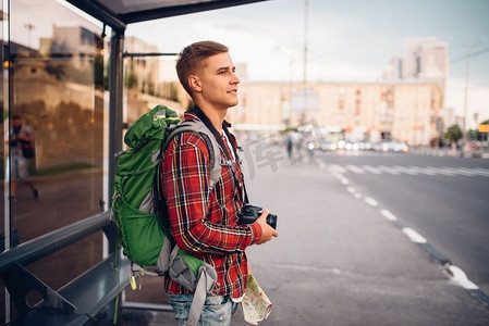 背着双肩背包的男游客在公共汽车站。暑期旅行，徒步旅行，观光，城市漫步