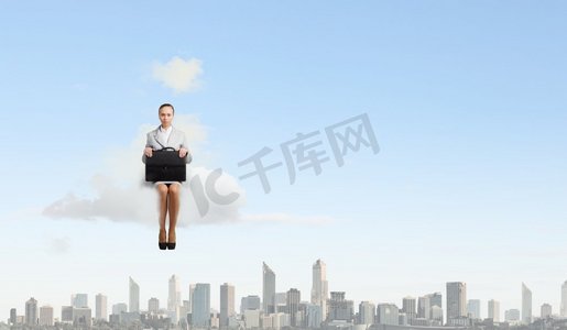 云上的女人摄影照片_云上的女人。年轻漂亮的女商人坐在城市上空的云端