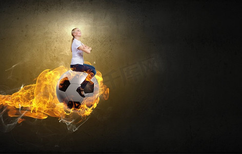 年轻女子坐在燃烧的足球上。女子骑行球