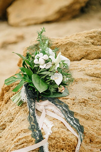 海边的一块砂岩上躺着一束来自粪便和玫瑰的新娘