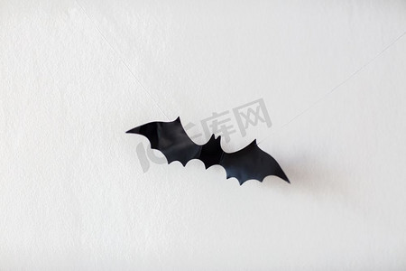 神秘聚会摄影照片_万圣节，装饰和可怕的概念-黑色蝙蝠挂在白色背景上的绳子上。挂在绳子上的蝙蝠的万圣节装饰