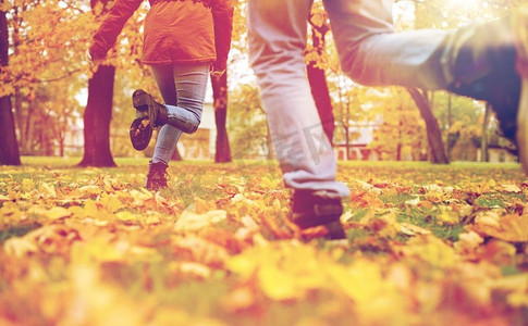 女人跑步摄影照片_爱情，关系，季节和人的概念--年轻情侣在秋日公园跑步。一对年轻夫妇在秋季公园跑步