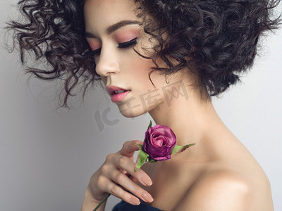 工作室时尚照片，美丽的年轻女子与紫罗兰玫瑰。情人节。春暖花开