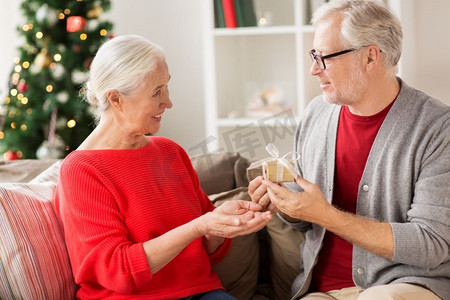 圣诞节、节假日和人们的概念-快乐的微笑着的老夫妇在家中有礼品盒。带着圣诞礼物的快乐微笑的高三夫妇