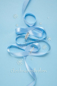 蓝色背景下用丝带和珠宝制作的圣诞树创意概念照片。