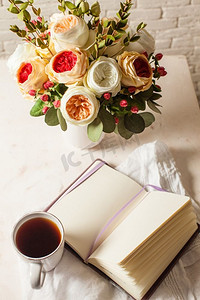 桌上放着一杯红茶、一本笔记本和一朵美丽的花。早晨计划一天的灵感。解决难题的启示