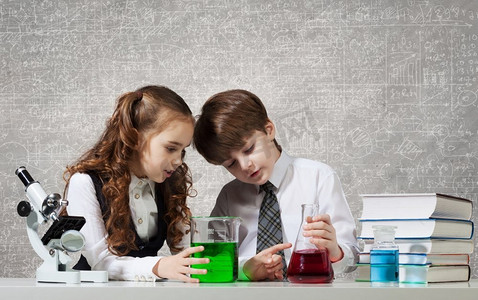 在化学课上。两个可爱的孩子在化学课上做实验