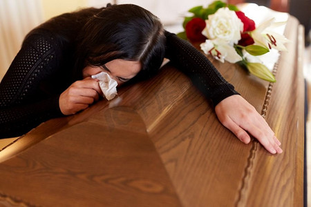 人与哀悼概念--教堂葬礼上哭泣的棺材女人。教堂葬礼上，一名抬着棺材的妇女哭泣