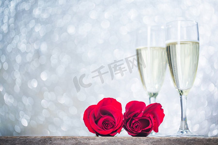 香槟和玫瑰。木质背景上的香槟和红玫瑰
