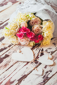 放在木板上的豪华玫瑰花束和木制的心形图案。一束玫瑰花