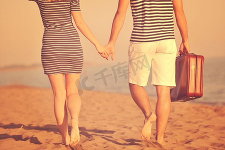 海滩情侣带着旅行包，代表着自由和有趣的蜜月概念