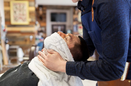 理发师在理发店用热毛巾软化男性面部皮肤。理发师用热毛巾柔软男士的脸