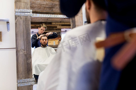美容、美发和人的概念-理发师和理发师在理发店剪发。一名男子和理发师在理发店理发