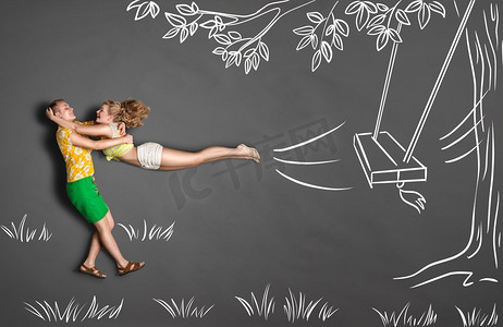 快乐情人节以粉笔画为背景的浪漫情侣的爱情故事概念。一名男子看到他的女朋友从树上的秋千上跳下来。