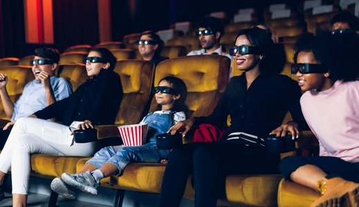 一群人观看电影与3D眼镜在电影院有兴趣看屏幕，令人兴奋和吃爆米花