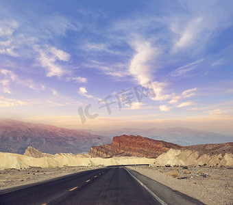 沙漠道路导致通过死亡谷国家公园日落，加利福尼亚州美国.