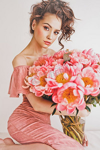 牡丹摄影照片_美丽的年轻女子戴着粉色牡丹的生活照片。作为礼物的花束。幸福的情感和喜悦。情人节。母亲节
