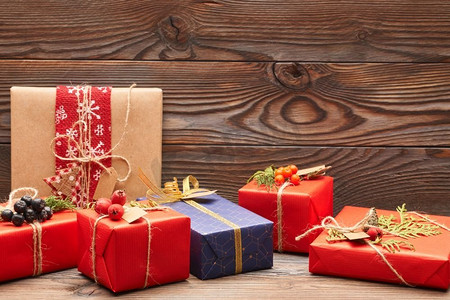 创造性地包装和装饰圣诞礼物，在木质背景的盒子里。复制空间。