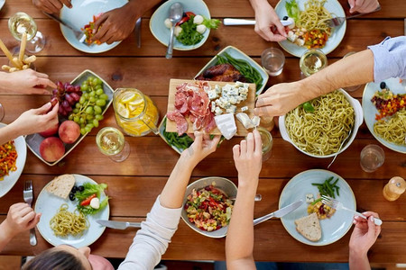 吃喝玩乐的概念--一群人在餐桌上与食物一起用餐。一群人带着食物在餐桌上吃饭