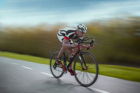 骑自行车的人戴着头盔，穿着运动服骑自行车，速度效果，侧视。骑自行车的人骑自行车，速度效果，侧视