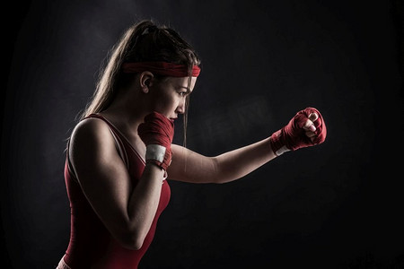 女拳击手戴着红拳绷带，训练着运动服。格斗运动理念