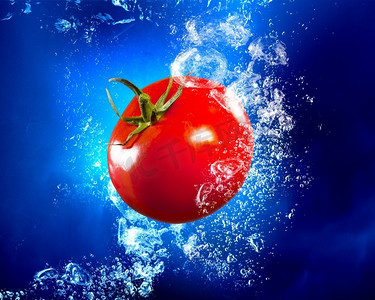 新鲜富含维他命的西红柿。成熟的西红柿落在清澈的蓝色水中