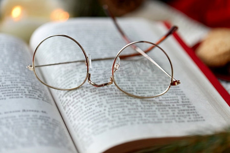 阅读，假期和休闲概念—圣诞节打开的书和眼镜特写镜头。关闭打开的书和眼镜在圣诞节