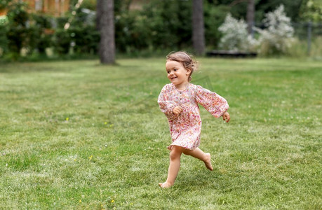 童年、休闲和人的概念快乐的小女婴奔跑在夏日的田野上。快乐的小女婴在夏日田野上奔跑