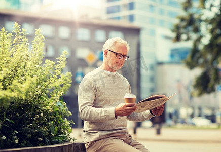 老报纸摄影照片_大众媒体、新闻和人物概念—在城市里读报纸喝咖啡的老年人。一位老人在看报纸喝咖啡