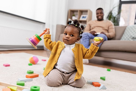 玩玩具的小女孩摄影照片_童年和人的概念-非洲裔美国小女孩在家里玩玩具积木。非洲女婴在家中玩积木玩具