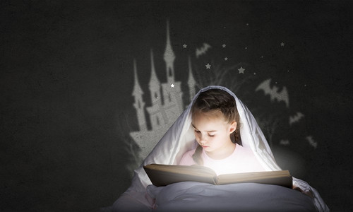 睡前阅读。可爱的女孩躺在毯子里，手里拿着书