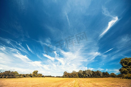 干的摄影照片_与一个戏剧性的蓝天的农村风景在夏末的干燥领域