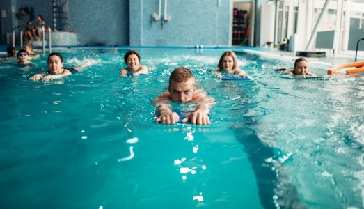 游泳框卡通框摄影照片_男教练游泳与女水中有氧运动组在游泳池锻炼。水上运动。男教练与女子水上有氧运动组游泳