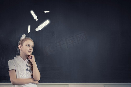 站在黑板旁的学龄期可爱而有思想的女孩。回到学校