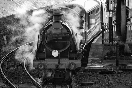 车站内历史悠久的老式蒸汽火车发动机，黑白全蒸汽吞吐