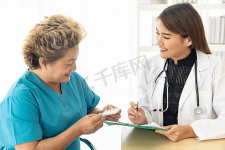 亚洲女医生在诊所医院的检查室里谈论处方药给老的老年病人。