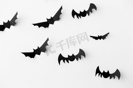 万圣节，装饰和可怕的概念—群黑色纸蝙蝠飞行在白色背景。一群黑色纸蝙蝠在白色背景