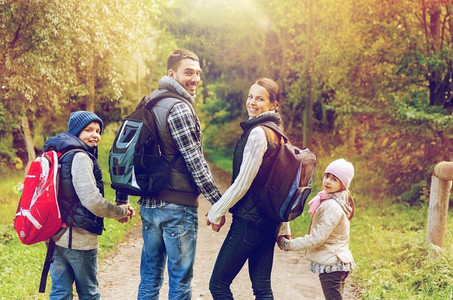 旅行，旅游和徒步旅行的概念-快乐的家庭背着背包在户外散步。背着背包的幸福家庭徒步旅行