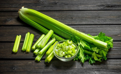 蔬菜切片摄影照片_新鲜多汁的芹菜在碗里。木背景。新鲜多汁的芹菜在碗里。
