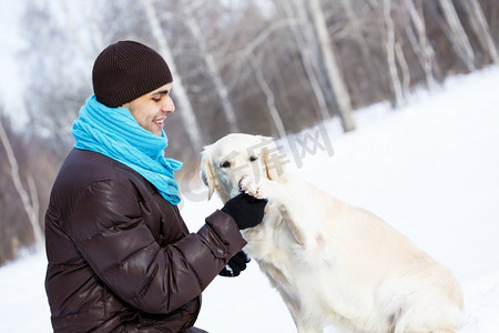 和他最好的朋友一起。一个男人带着拉布拉多犬在冬季公园散步