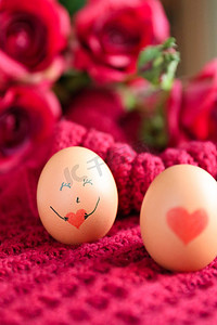 红色桃心摄影照片_画着桃心笑脸表情的鸡蛋在红色背景上