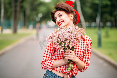 微笑标语摄影照片_带着花束的美女，复古的美国时尚。Pin Up风格的可爱微笑的女人