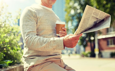 老年人和人的概念—坐在街边长凳上喝咖啡读报纸的老年人。高级男子与咖啡阅读报纸户外