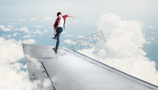 一个用翅膀滑滑板的男孩。滑冰男孩在飞行的飞机边缘做特技