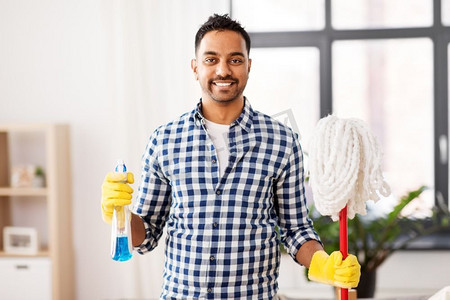 清洁，家务和家政概念—微笑的印度男子与拖把和清洁剂在家里。印度男子与拖把和清洁剂清洁在家里
