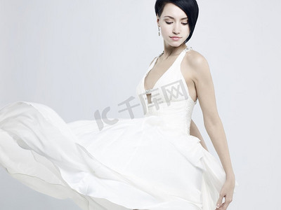 穿着飘逸的白色连衣裙的美丽年轻女士的时尚照片