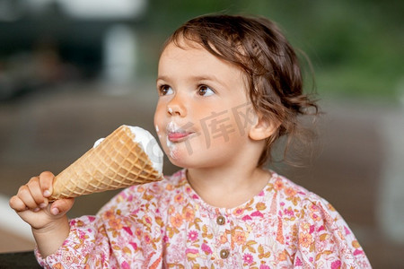 童年、休闲和人的概念--快乐的小女婴吃冰淇淋。快乐的小女婴吃着冰淇淋
