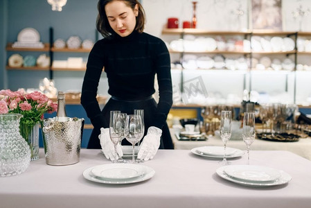女服务员戴着手套把盘子放在餐桌上。服务、节日晚宴装饰、节日餐具